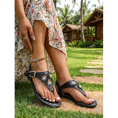Braune Zehentrenner-Sandalen aus Kunstleder für Damen mit 3D-Blumenapplikation – bequemer, flacher T-Riemen-Sandalen im Boho-Resort-Stil für Strandurlaube und Spaziergänge in tropischen Gärten. Image