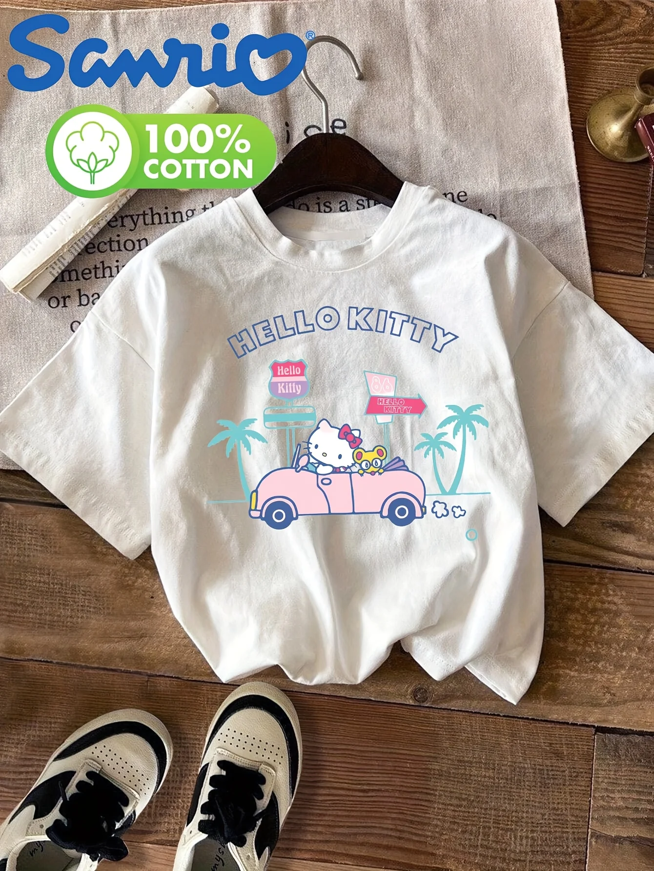 Sommerlicher neuer Trend für Kinder-T-Shirts: Niedliches Kätzchen, das ein rosa Auto fährt, im Urlaubsthema von Sanrio, aus 100 % reiner Baumwolle, weiches Material Image