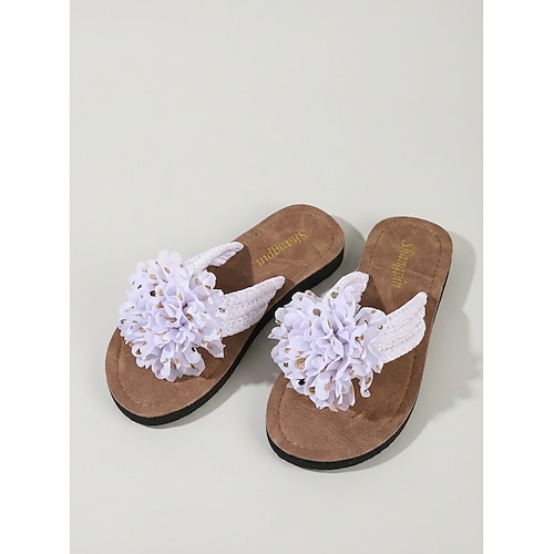 Romantische weiße Zehentrenner-Sandalen mit Blumenmuster für Damen – bequeme flache Flip-Flops mit großer, gepunkteter Blumenapplikation für den Poolbereich von Luxushotels und Strandurlaube. Image